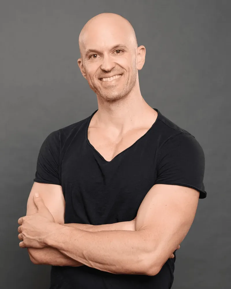 Joe, smiling, arms crossed, in a black t-shirt