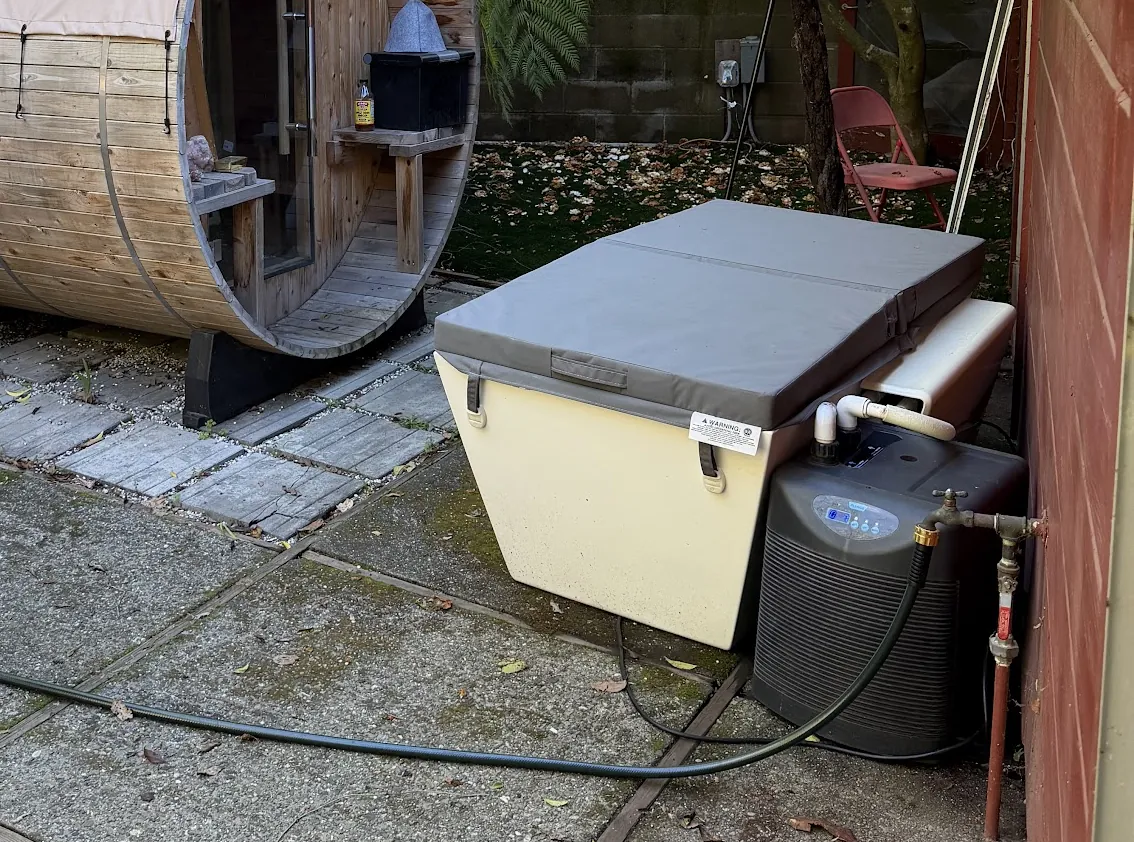 The covered cold plunge tub and its chiller, steps from the cedar barrel sauna